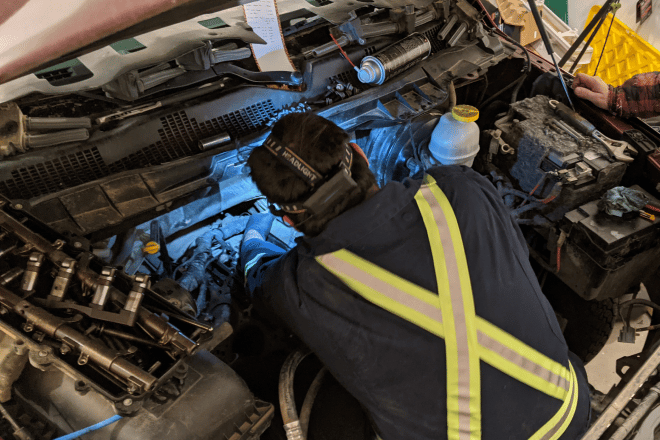 Kolby White diagnosing a mechanical problem in an engine bay